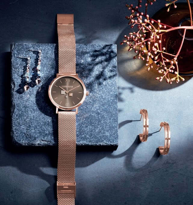 a watch and a pair of earrings on a table