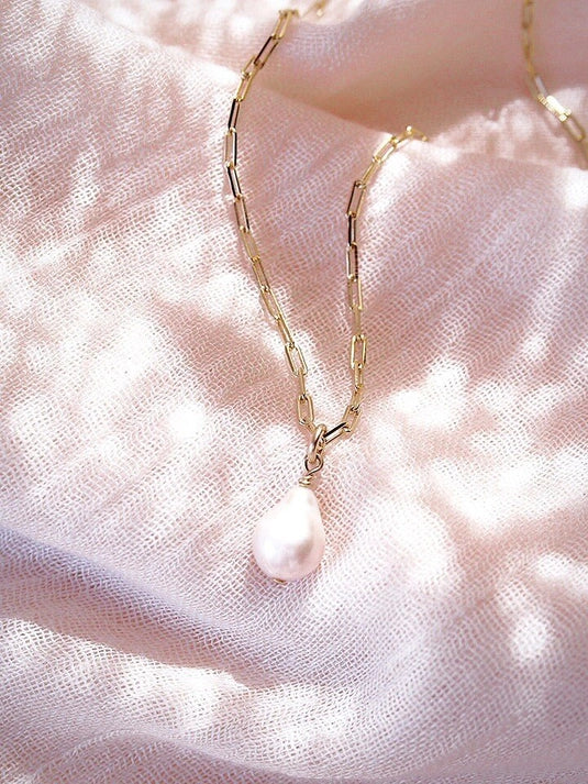 pearl dangling from a gold filled paperclip chain.